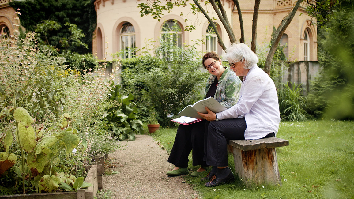 Arbeitsstellenleiterin Dr. Brigitte Bulitta (vorn) und wissenschaftliche Mitarbeiterin Dr. Almut Mikeleitis-Winter im Garten der Akademie