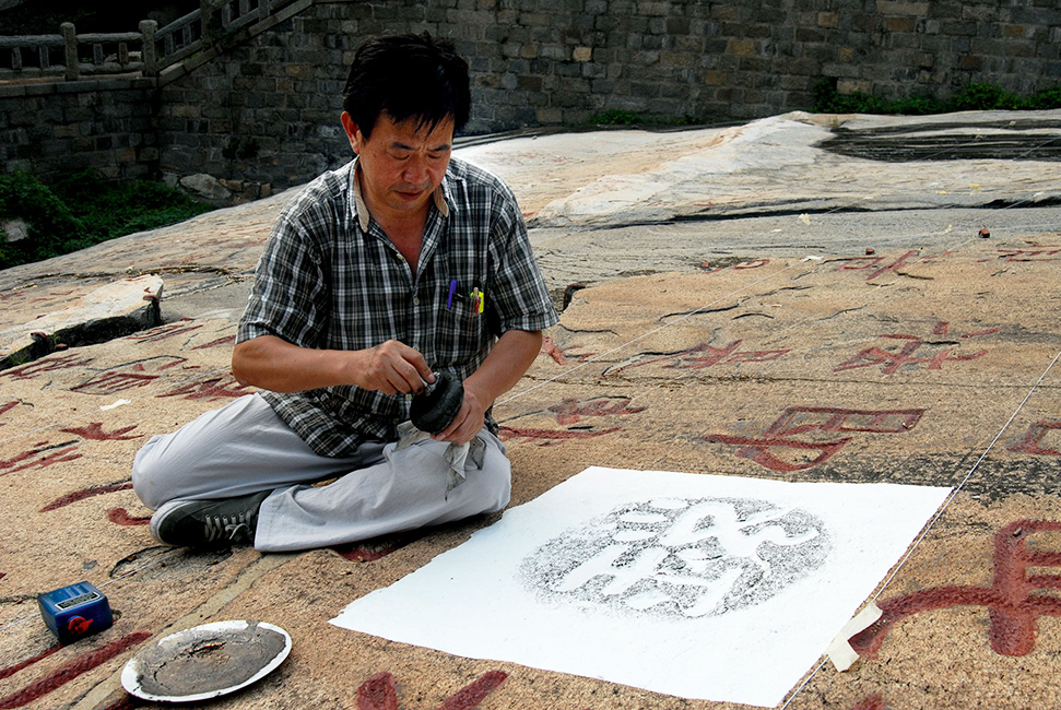 Herr Lai Fei vom Museum f&uuml;r die Kunst der Steinbearbeitung in Jinan stellt auf dem Diamantsutra eine Abreibung des Zeichens „Sutra" her.
