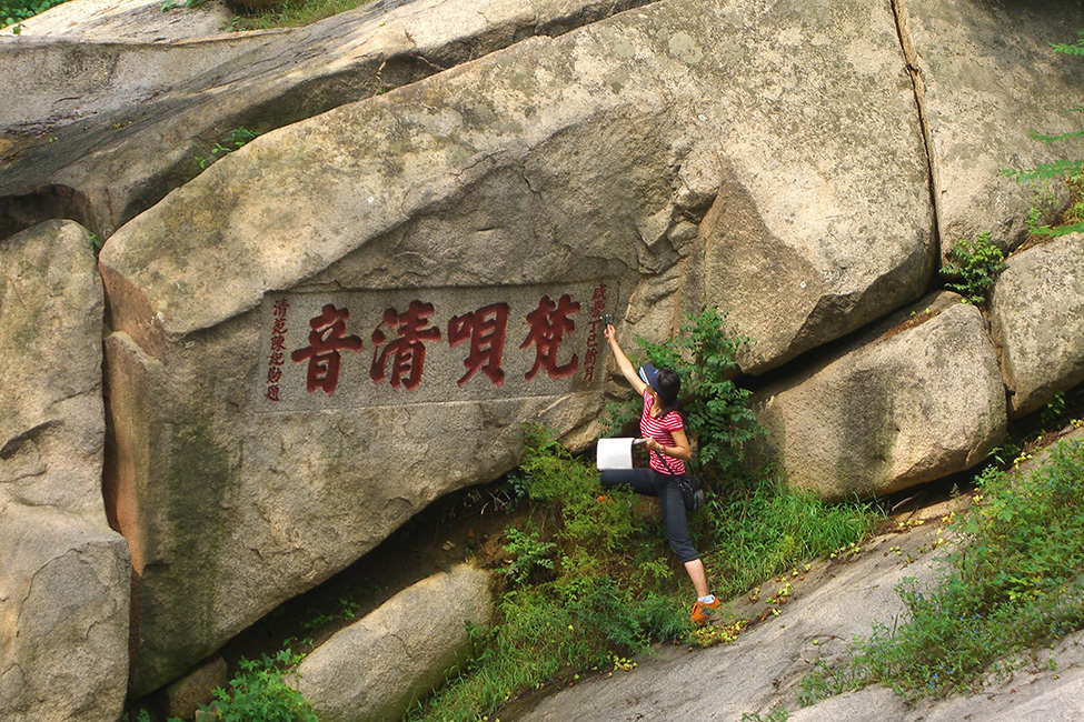 Eine Mitarbeiterin vermisst die Schriftzeichen des 1857 eingemei&szlig;elten Kolophons: „Ein klarer Klang buddhistischer Ch&ouml;re."
