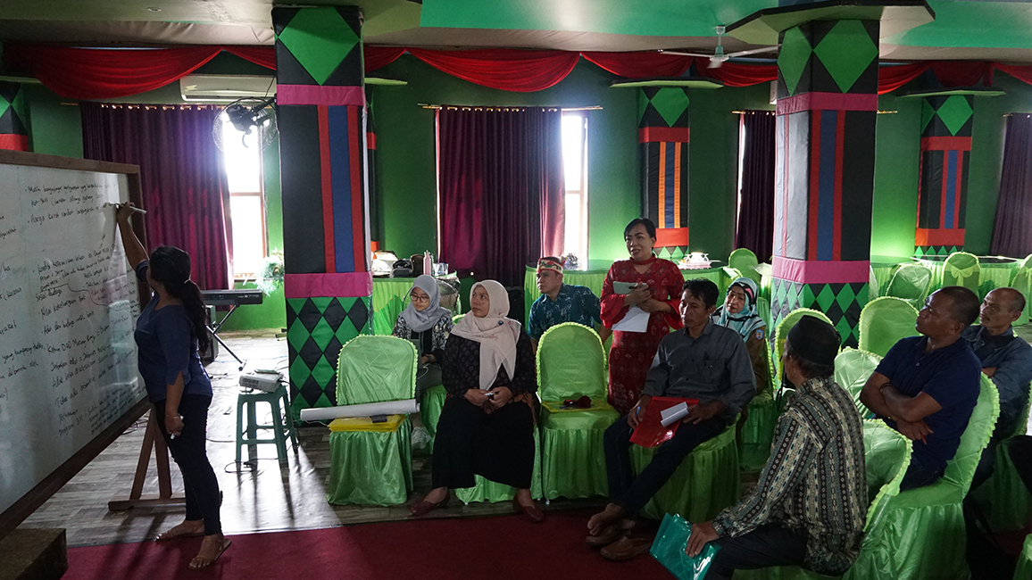 Mehrere Personen diskutieren miteinander, eine Person schreibt an eine Tafel