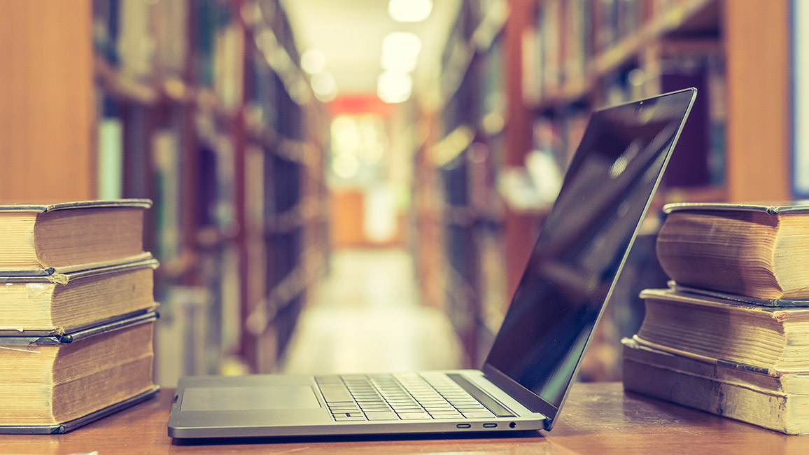 Laptop zwischen B&uuml;chern in Bibliothek